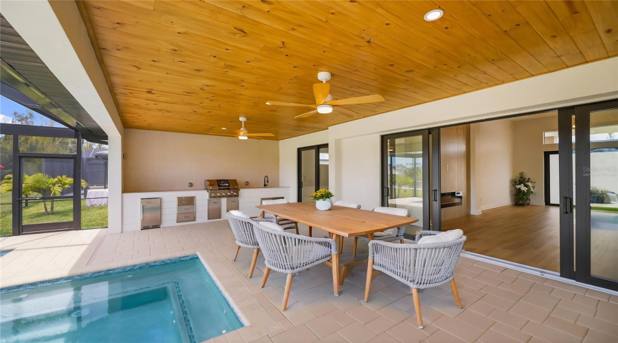 Virtually Staged Covered Lanai With Outdoor Kitchen And Poolside Dining.