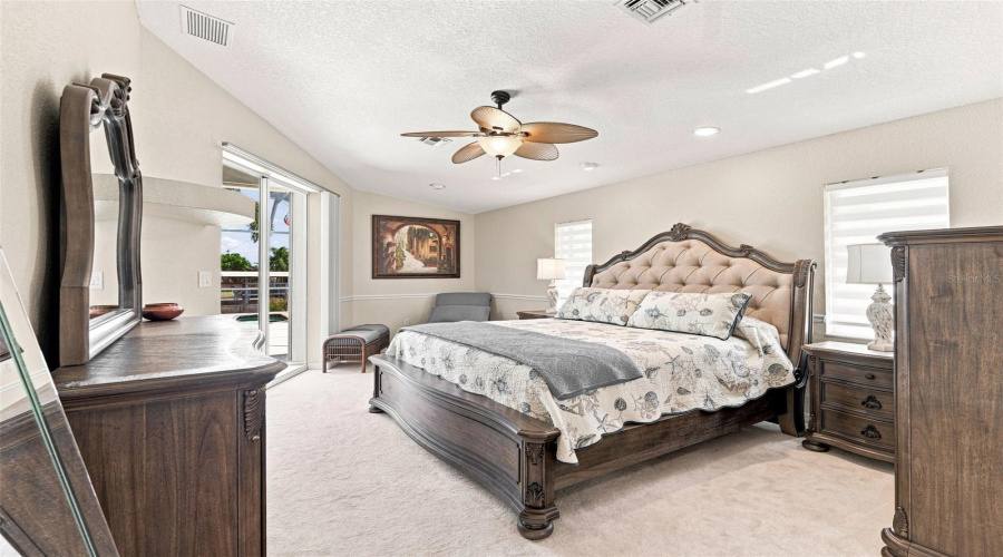 Relaxing Primary Suite With Ceiling Fan And Sliding Doors To Pool