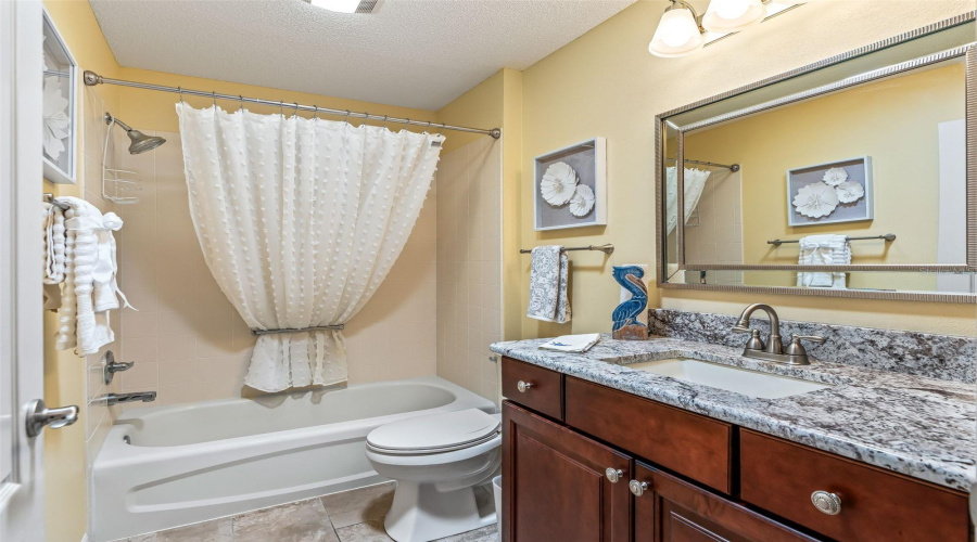 Upgraded Guest Bathroom With Plenty Of Counterspace On The Granite Rich Toned Vanity With A Tub And Shower Unit.