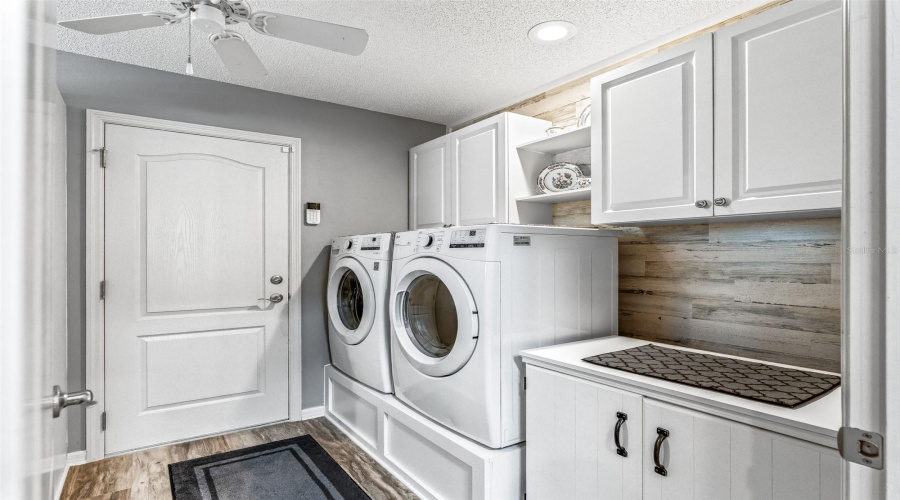 Well-Equipped Interior Laundry Room Features A Side-By-Side Washer And Dryer, Abundant Cabinetry, A Utility Sink, And Generous Counter Space For Folding And Storage.