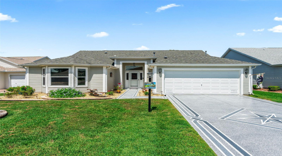 Bright And Welcoming Exterior Featuring A Neatly Landscaped Lawn, Covered Front Entry, And Spacious, Custom Painted Driveway Leading To The Two-Car Garage.