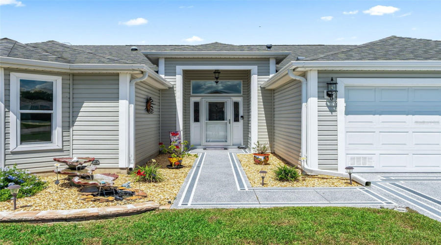 Welcoming Covered Entry With Glass-Accented Front Door, Sidelights, And A Decorative Walkway Offers A Polished First Impression.