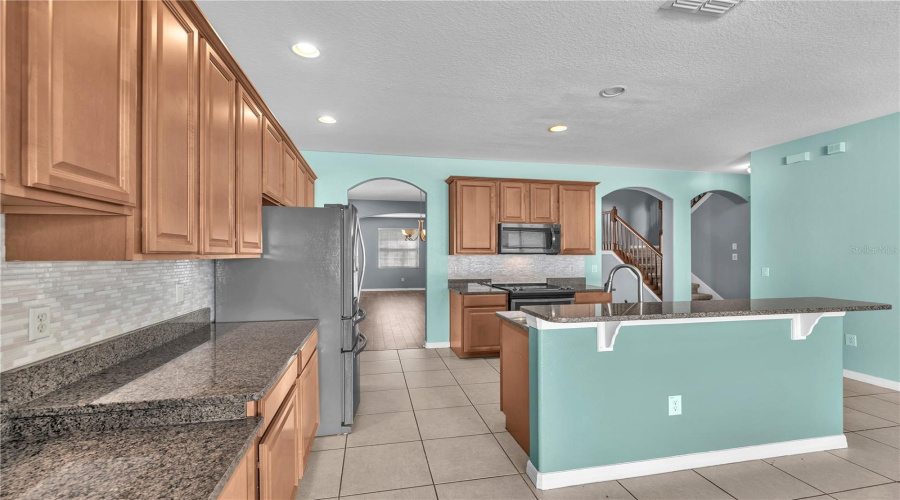 Designed To Impress, The Kitchen Features Polished Granite Countertops, A Large Center Island With An Undermount Sink, Rich 42-Inch Maple Cabinetry With Roll-Out Shelves, A Spacious Pantry, Breakfast Bar, Built-In Desk, Sunny Breakfast Nook, And Stainless Steel Appliances, Including A Built-In Microwave, Glass-Top Range, And Side-By-Side Refrigerator.