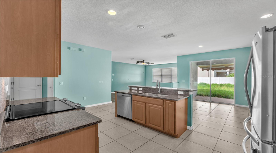 Stainless Steel Built-In Microwave, Glass-Top Range, Side-By-Side Refrigerator, Dishwasher And Sink In Island.