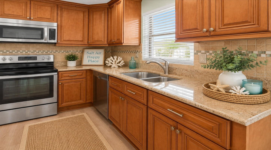 •  Kitchen: Virtually Staged – Coastal-Inspired Kitchen Featuring The Existing Cabinetry, Granite Countertops And Backsplash, With Added Décor And Refrigerator.