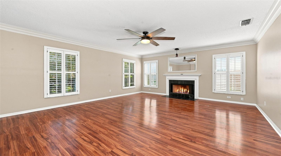Formal Living Room With Wood Burning Fireplace, Crown Molding And Plantation Shutters