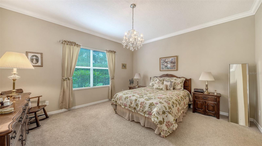 Serene Primary Suite With Crown Molding And Chandelier