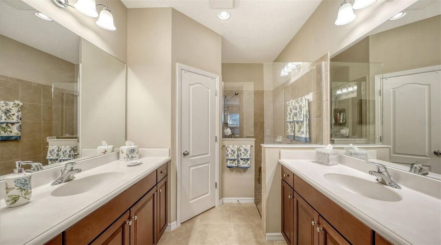 Dual Split Vanities, Frameless Glass Walk-In Shower, And A Private Water Closet
