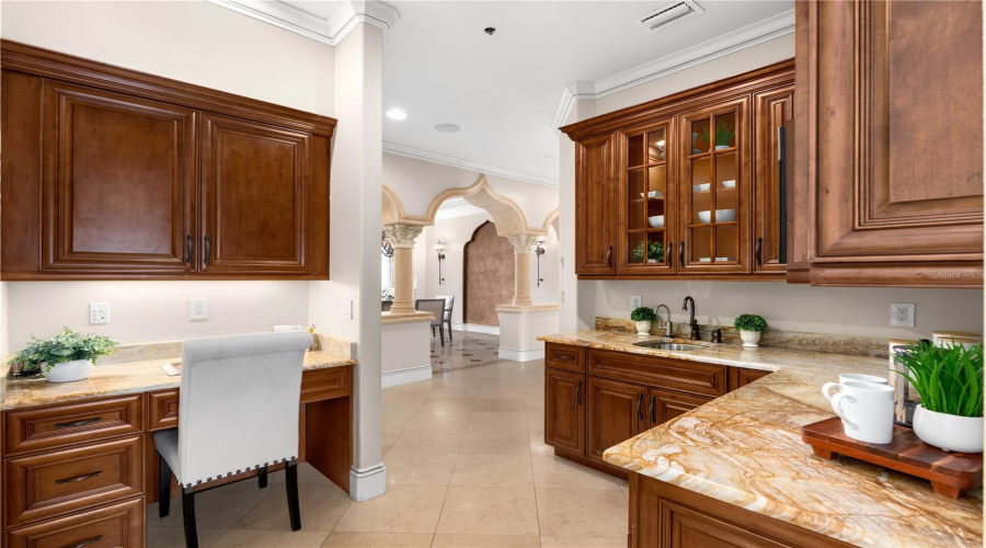 A Beautifully Appointed Butler'S Pantry Offers Rich Custom Wood Cabinetry, Natural Stone Countertops And Dedicated Preparation Space For Effortless Entertaining.