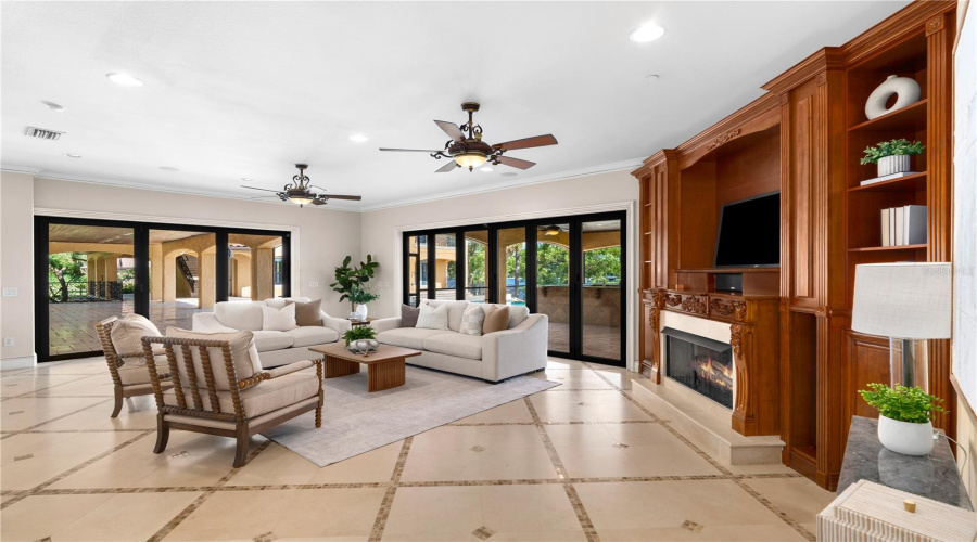 The Lakefront Family Room Blends Warmth And Sophistication With A Gas Fireplace, Custom Built-In Wood Cabinetry And Expansive Views Toward The Resort-Style Grounds And Lake Mary Beyond.