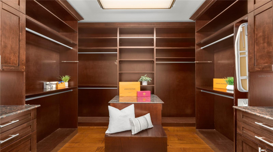 A Bespoke Walk-In Wardrobe Is Finished In Rich Custom Wood Cabinetry With Extensive Hanging Areas, Shelving, Drawers And Thoughtfully Designed Storage For The Secondary Primary.