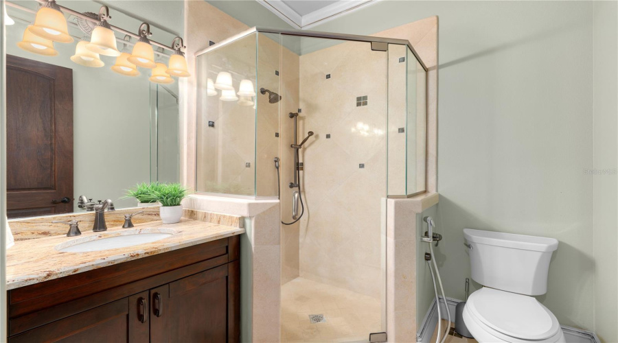 A Private En-Suite Bath Features A Glass-Enclosed Walk-In Shower, Custom Vanity And Coordinated Tile Finishes.