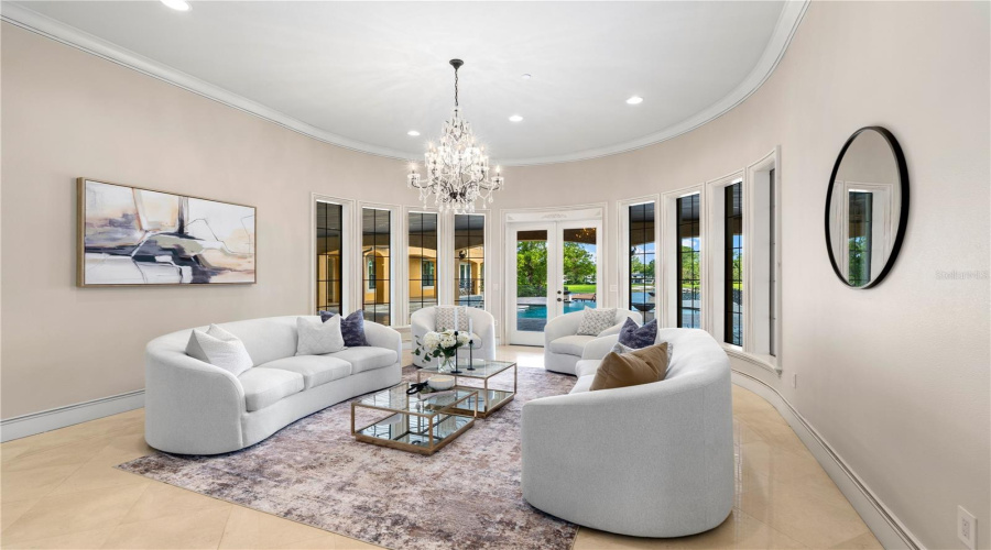 Elegant Formal Living Room Framed By A Graceful Wall Of Windows Creates A Sophisticated Setting Filled With Natural Light And Views Across Lake Mary.