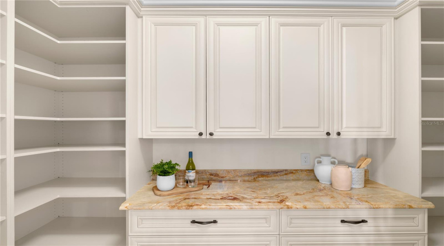 Custom Built-In Cabinetry In The Walk-In Pantry, Topped With Natural Stone, Provides Elegant Additional Storage And Prep Area.