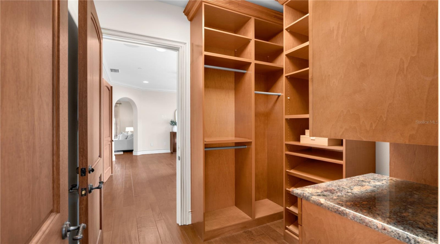 A Custom Walk-In Wardrobe Offers Thoughtfully Designed Built-In Shelving, Hanging Areas And Stone-Topped Cabinetry.