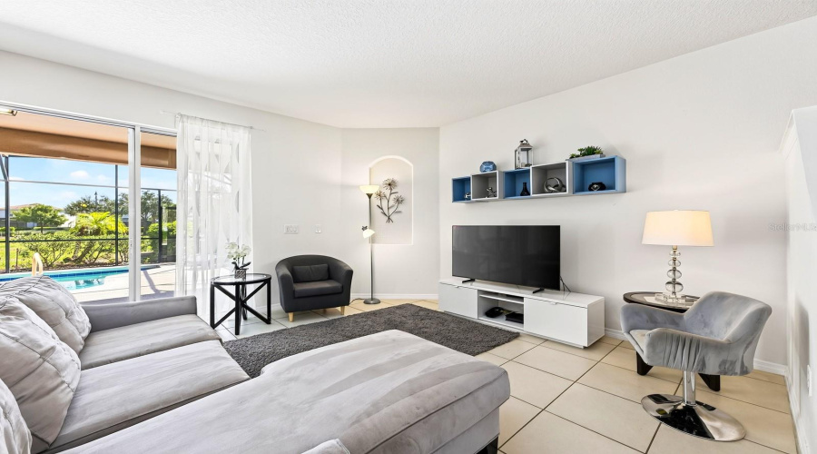 Abundant Natural Light And Easy-Care Tile Flooring Create A Welcoming Atmosphere In The Living Room.