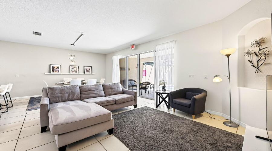Abundant Natural Light And Easy-Care Tile Flooring Create A Welcoming Atmosphere In The Living Room.