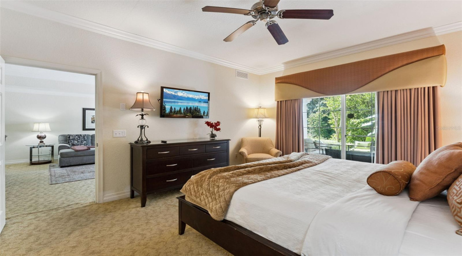 Primary Suite &Amp; Patio Access: Light-Filled Primary Bedroom Complete With A Ceiling Fan, Accent Seating Area, And Sliding Glass Doors Opening To The Outdoor Patio.