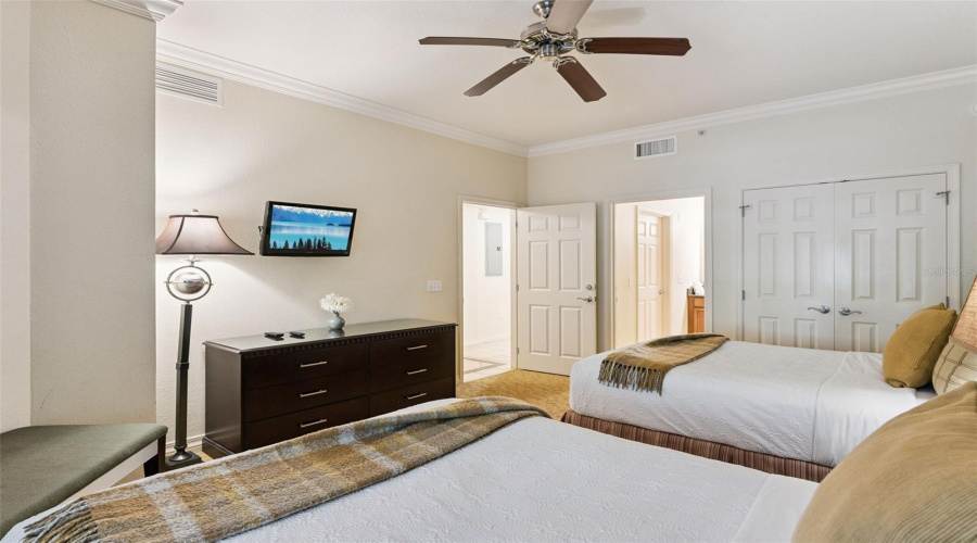 Double Bedroom Alternate View: Angle Of The Double Guest Room Showcasing A Matching Dresser, Wall-Mounted Tv, Double Bi-Fold Closet Doors, And Adjacent Hallway Access.