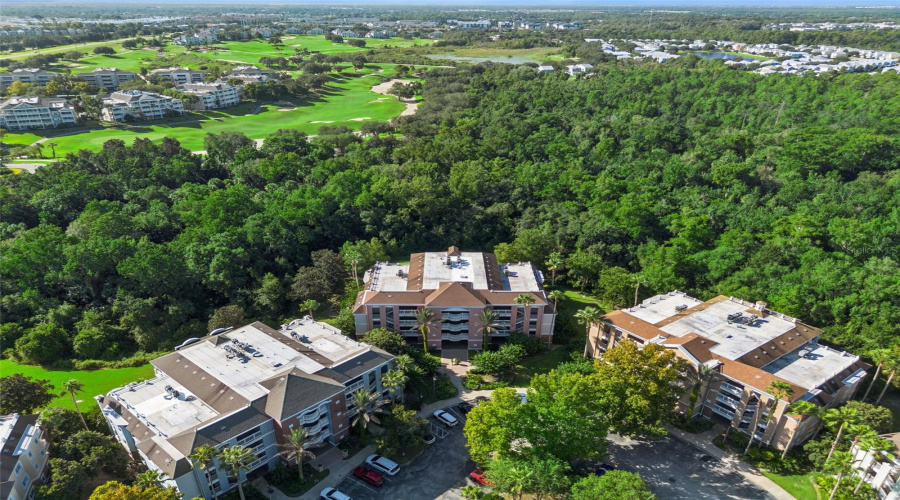 Overhead Conservation View: Overhead Drone Perspective Highlighting The Secluded Setting Of The Residential Buildings Surrounded By Dense Tree Canopy And Neighboring Golf Greens.