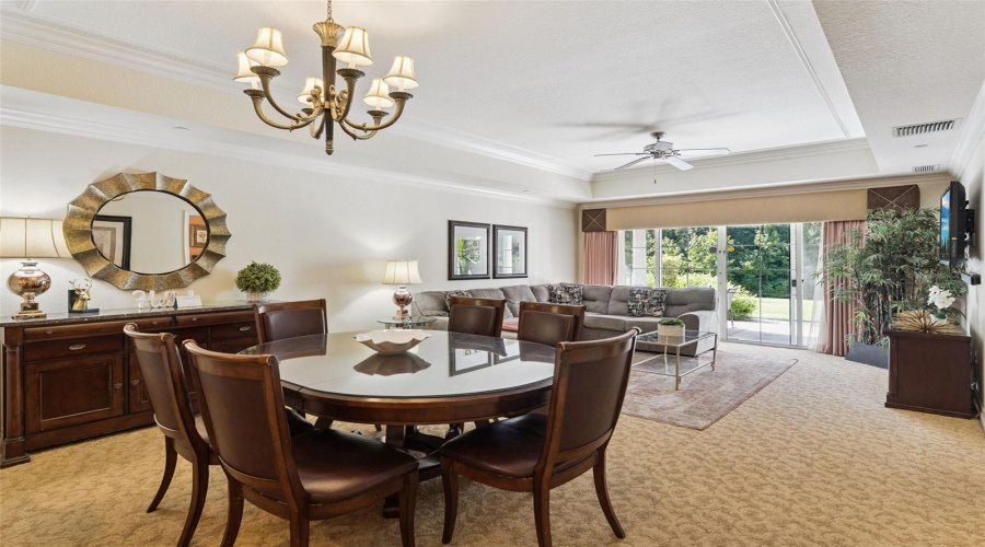 Dining &Amp; Living Area: Expansive Open-Concept Dining Room Featuring A Classic Chandelier, Tray Ceiling Detailing, And A Seamless Transition Into The Main Living Space.