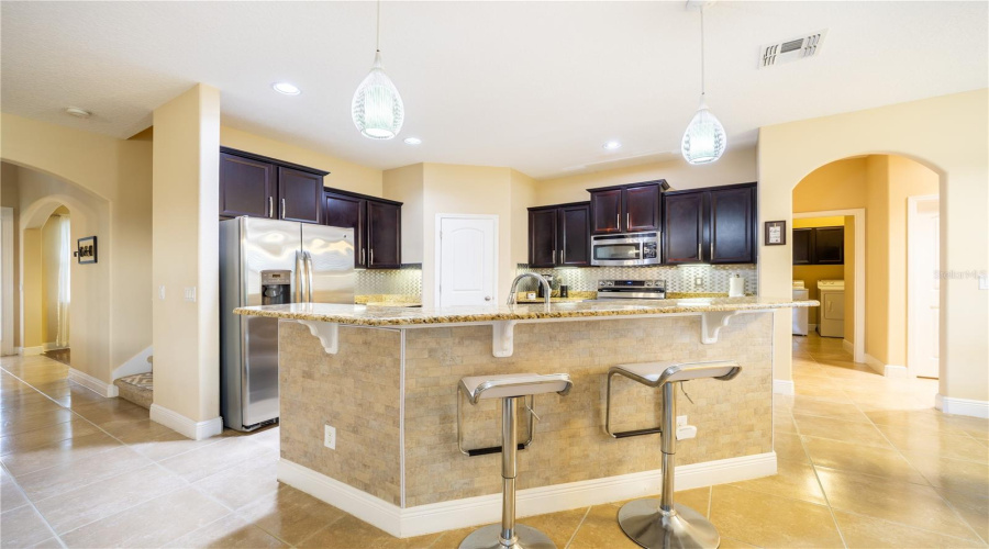 Kitchen With Large Island, Granite Countertops And Stainless Steel Appliances
