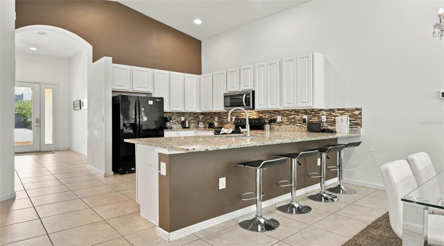 Open Kitchen With 42&Quot; White Cabinets, Black Whirlpool Appliances And Granite Countertops.
