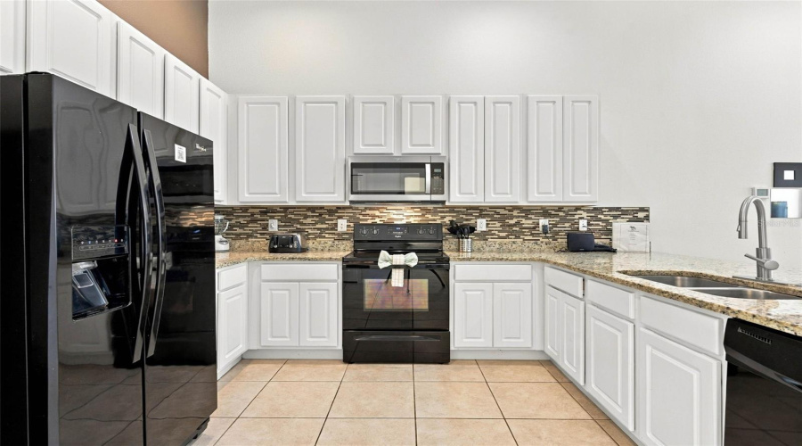Open Kitchen With 42&Quot; White Cabinets, Black Whirlpool Appliances And Granite Countertops.