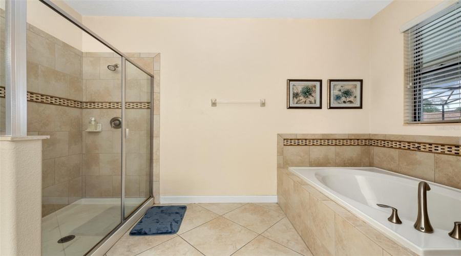Primary Bathroom Featuring A Soaking Tub And Separate Glass-Enclosed Shower