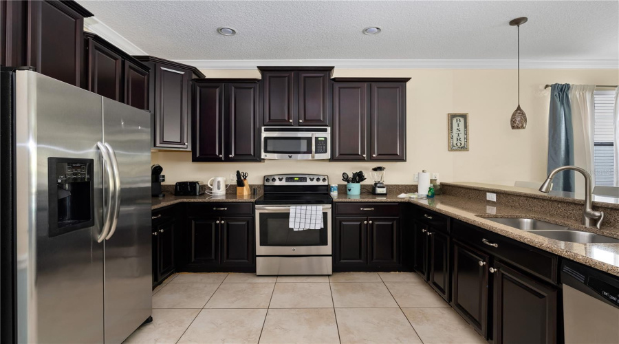 Spacious Kitchen Featuring Rich Espresso Cabinetry, Granite Countertops, Stainless Steel Appliances And Breakfast Bar Seating